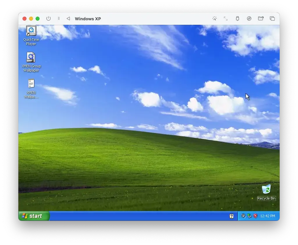 Windows XP desktop in UTM on macOS: Bliss wallpaper, QuickTime Player, and X-Men promo assets on the desktop.